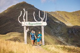 Familie wandert über die Gipfelwelt durch ein Schild hindurch