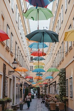 Kleine Gasse bei Tageslicht mit bunten Regenschirmen in der Luft als Dekoration