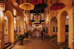 Innenhof mit Backsteinpflaster Boden und bunten Regenschirmen in der Luft als Dekoration